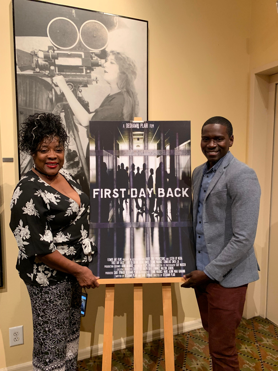 Maurice Mack at the First Day Back premiere, beside the film's poster
